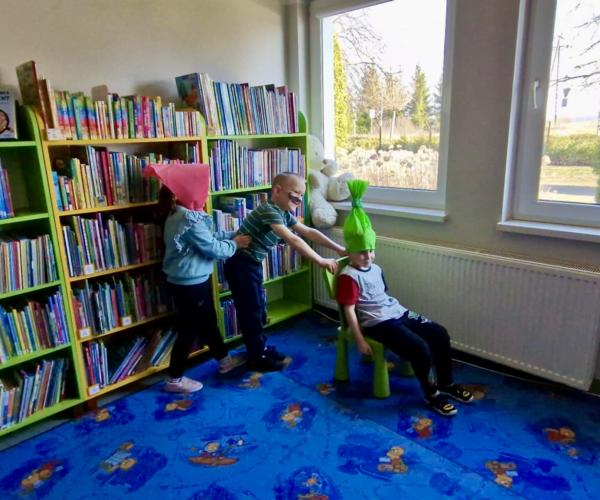 Dziecko siedzi na krześle za nim stoi dwójka dzieci 