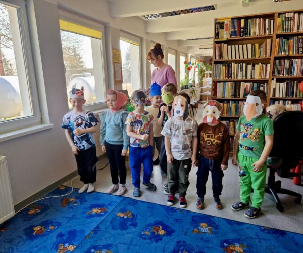 Bibliotekarz stoi z dziećmi w maskach zwierząt