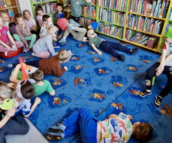 Kilkoro uśmiechniętych dzieci leży na dywanie 